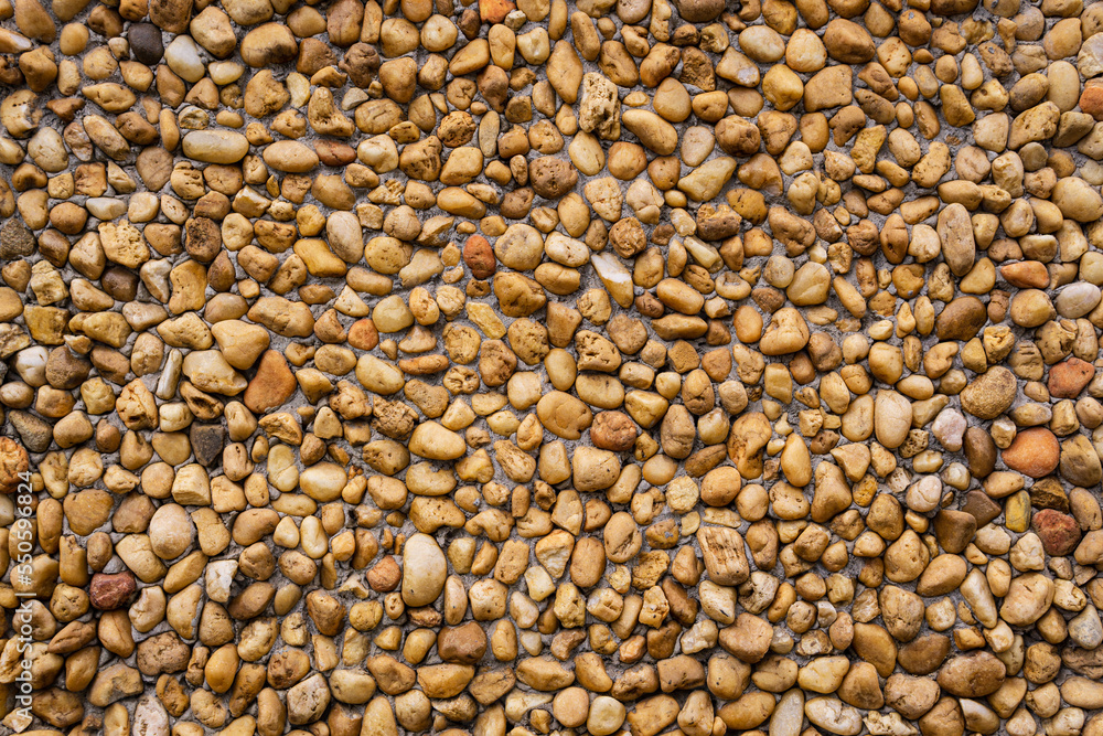 Natural background wall with beige and brown pebbles and stones Natural background wall with beige and brown pebbles and stones