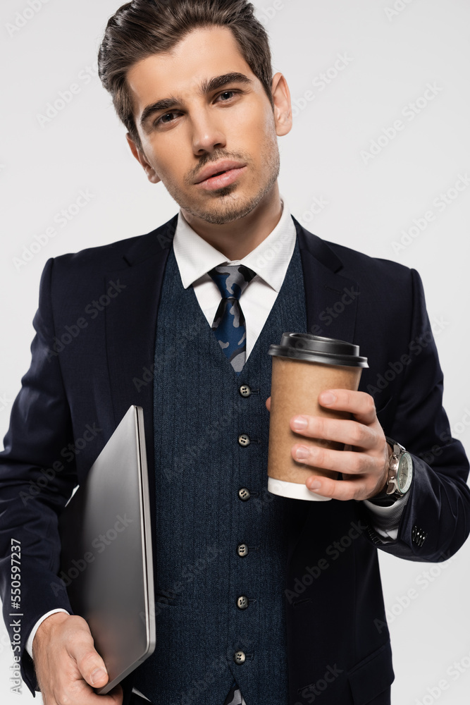 young businessman holding paper cup and laptop isolated on grey young businessman holding paper cup and laptop isolated on grey