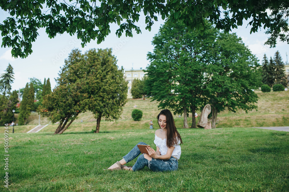 Young brunette woman, girl working with laptop, tablet and phone in green field, park with sunshine Young brunette woman, girl working with laptop, tablet and phone in green field, park with sunshine