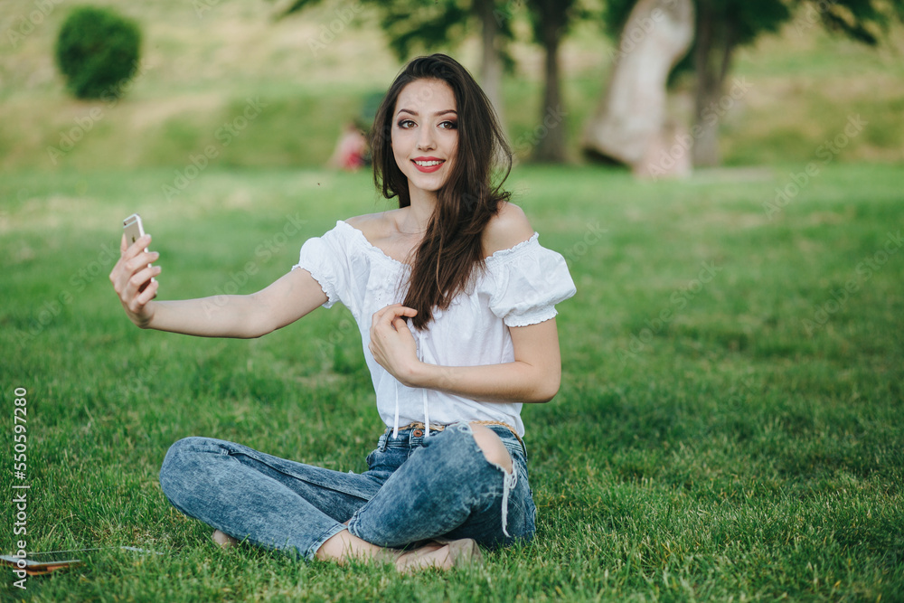 Young brunette woman, girl working with laptop, tablet and phone in green field, park with sunshine Young brunette woman, girl working with laptop, tablet and phone in green field, park with sunshine