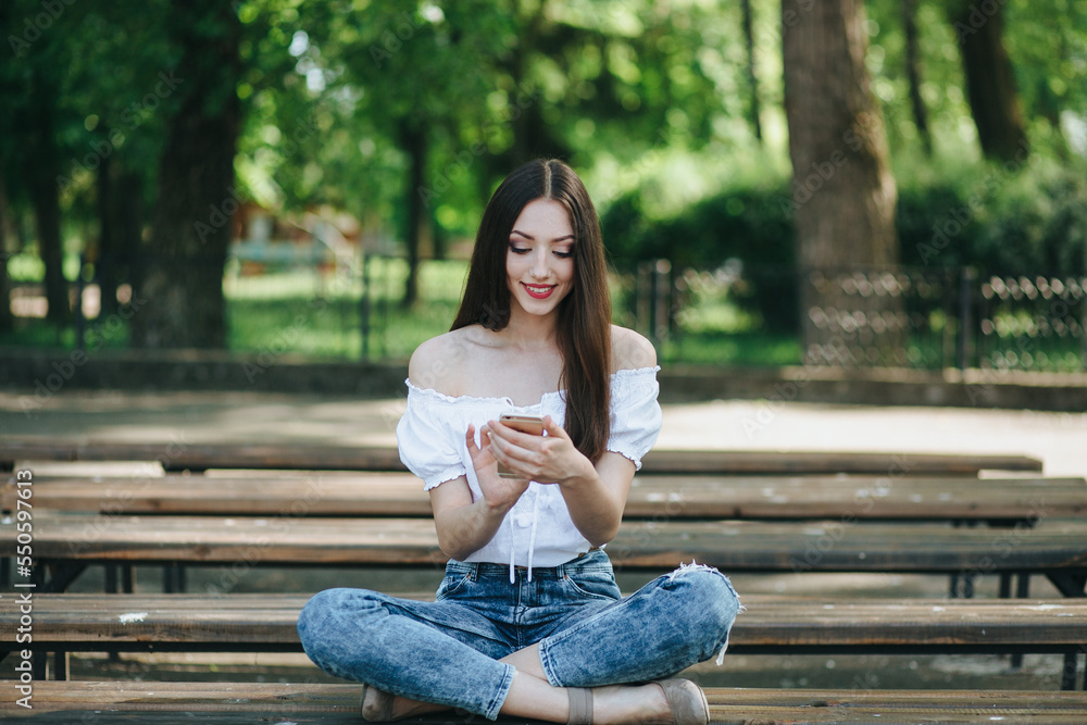 Young woman with smartphone and laptop on the bench Young woman with smartphone and laptop on the bench