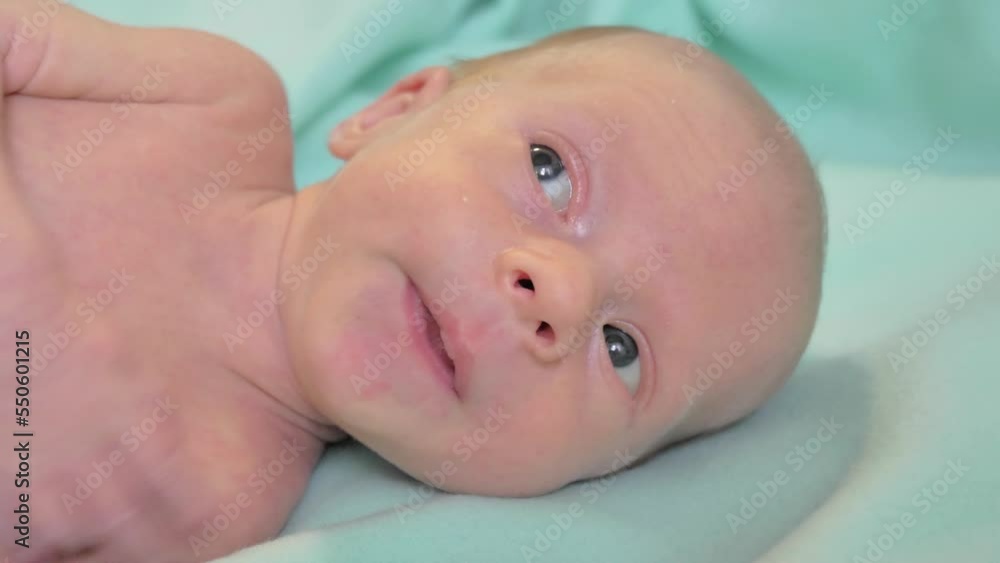 Portrait of a newborn baby. Caucasian child laying on the bed and looking around Portrait of a newborn baby. Caucasian child laying on the bed and looking around