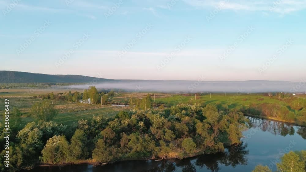 Aerial view of a river surrounded with green trees at foggy sunrise. Calm morning and relaxing atmosphere. Beautiful landscape Aerial view of a river surrounded with green trees at foggy sunrise. Calm morning and relaxing atmosphere. Beautiful landscape
