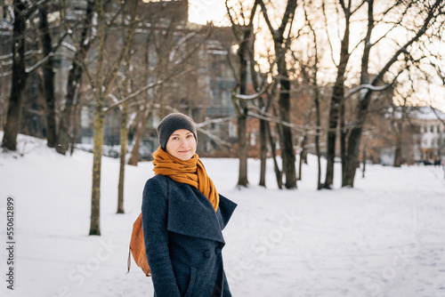 A woman in warm winter clothes looks into the camera and smiles in winter