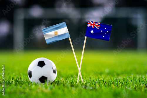 Argentina - Australia. Eight final, Round of 16 football match. Handmade national flags and soccer ball on green grass. Football stadium in background. Black space. photo