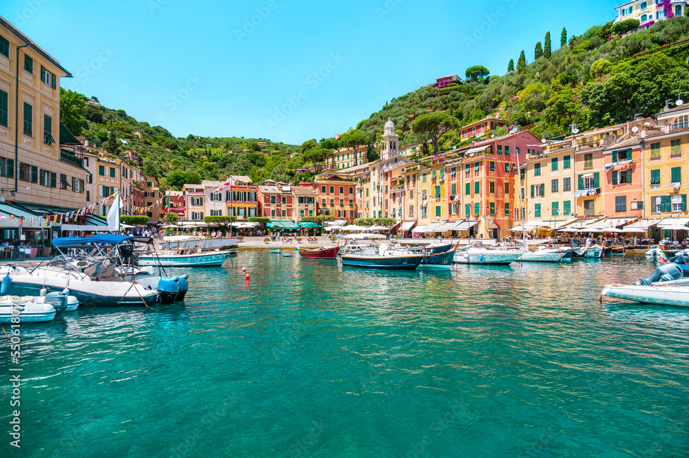 View from the sea of a coastal Italian tourist town with bright, multi-colored facades of houses against the backdrop of a blue sky and sea water