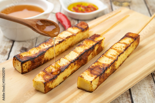 Billede på lærred Grilled Rennet or Coalho cheese on a wooden board with sugar syrup and pepper