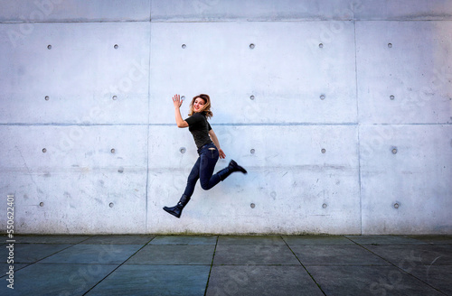 woman in black clothes jumping in front of grey wall