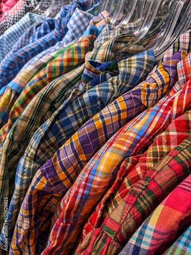 Many colorful checkered formal shirts hanging on a racks