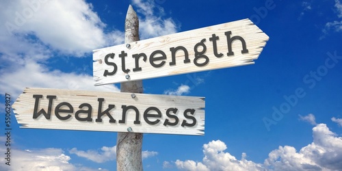 Strength and weakness - wooden signpost with two arrows photo