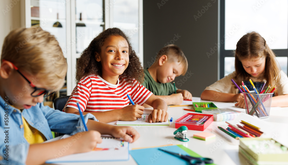 Cheerful multiracial children solving test with classmates Cheerful multiracial children solving test with classmates