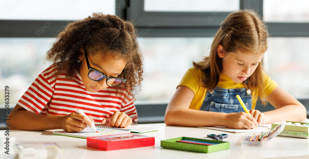 Focused multiracial children solving test with classmates
