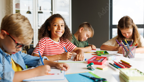 Cheerful multiracial children solving test with classmates