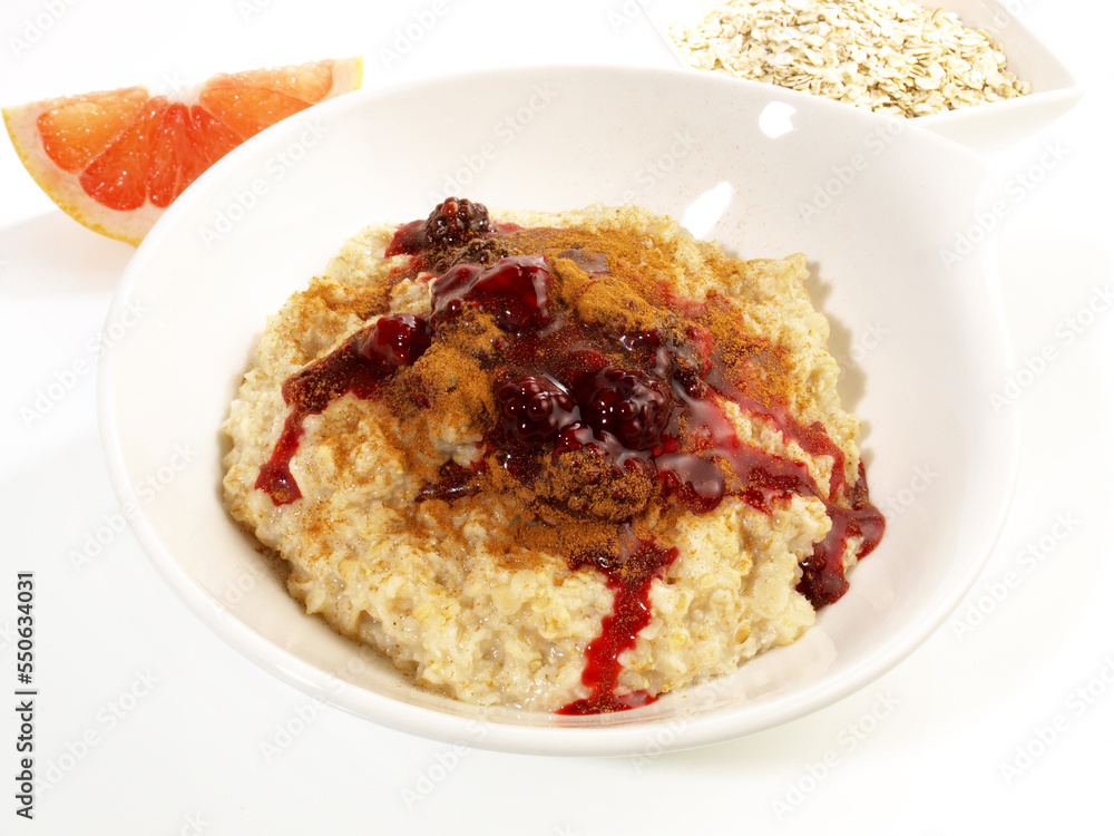 Porridge in a white Bowl; Oatmeal with Berries and Cinnamon isolated on white Background Porridge in a white Bowl; Oatmeal with Berries and Cinnamon isolated on white Background