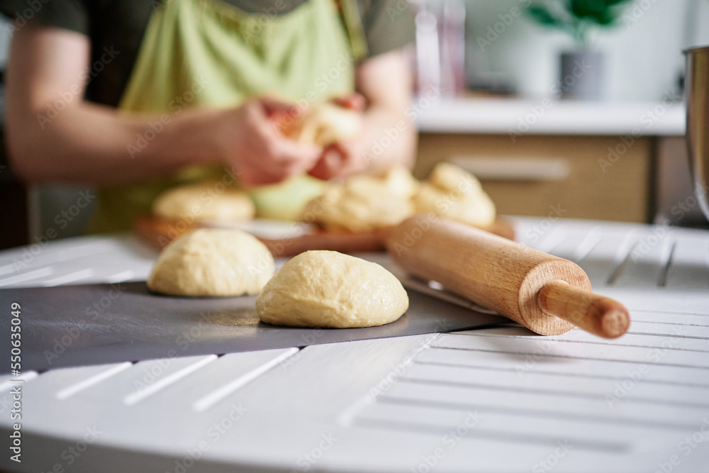 Dough balls preparation concept. Unrecognizable baker working with dough on background, Fresh raw dough. Preparing pizza dough on a table at kitchen at home. High quality image
