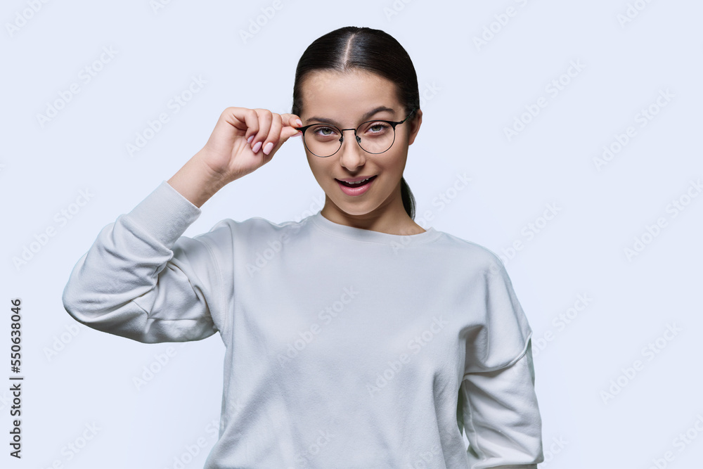 Teenage girl student holding glasses looking at camera on white background Teenage girl student holding glasses looking at camera on white background