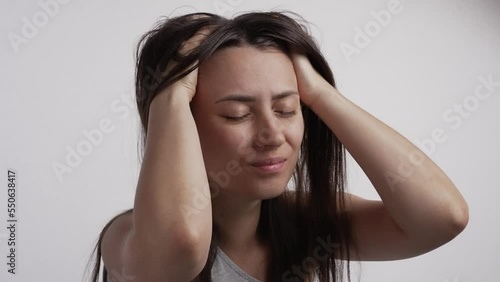 Woman scratching itchy scalp on white background photo