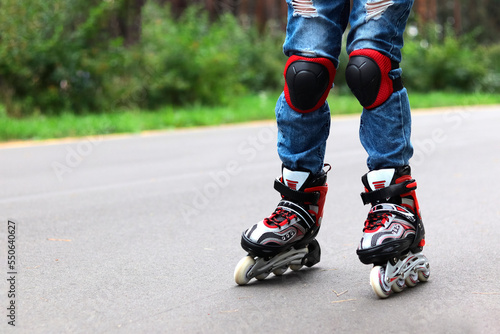 Close-up of children's feet in roller skates, a child learns to ride roller skates in protective gear
