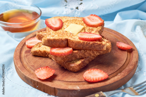 Slices of bread, French Toast garnished with strawberries, on morning scene.