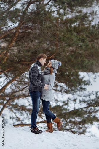 The couple hugs and smiles while standing in the snow.