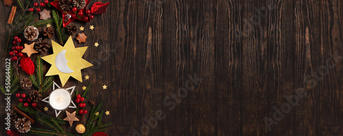 Winter solstice day, December 21. Sun and moon symbol, Christmas trees, pine cones, paddub branches with red berries, candle on dark wooden background, top view. photo