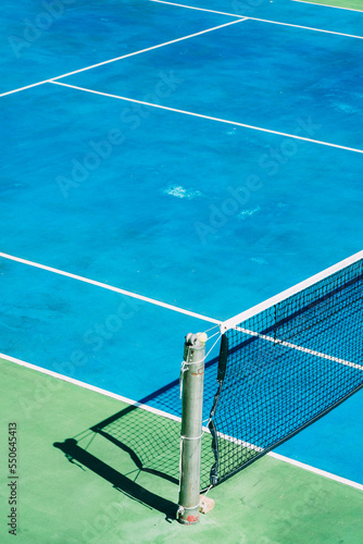 Deserted tennis court with greentrees in background in a public park on a sunny summer morning © yaophotograph