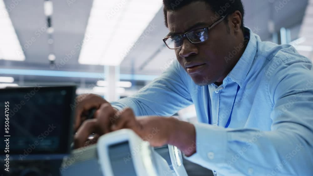 Close Up Portrait of a Young Black Multiethnic Engineer Screwing In a Microchip to a Futuristic Robot Dog Project. High Tech Research Laboratory with Modern Equipment. Close Up Portrait of a Young Black Multiethnic Engineer Screwing In a Microchip to a Futuristic Robot Dog Project. High Tech Research Laboratory with Modern Equipment.