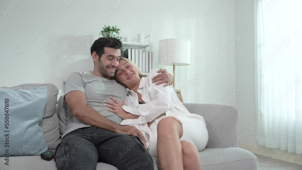 Young caucasian couple relaxing together on sofa in living room at home. Young caucasian couple relaxing together on sofa in living room at home.