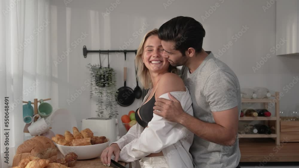 Beautiful young Caucasian couple talking and smiling in kitchen at home. Beautiful young Caucasian couple talking and smiling in kitchen at home.