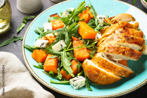 Warm salad with baked chicken breast, pumpkin, blue cheese and arugula. Healthy diet food.