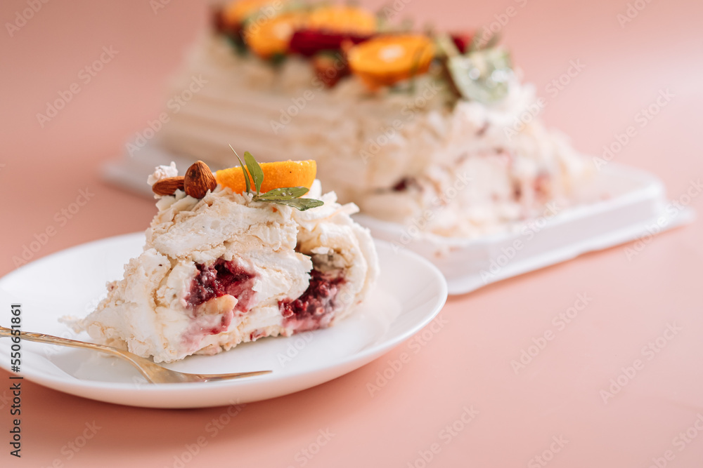 Festive meringue roll cut on white plate with fork on pink background. Festive meringue roll cut on white plate with fork on pink background.