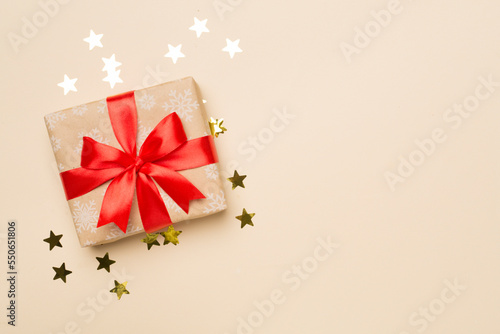 Gift box and stars confetti on color background, top view