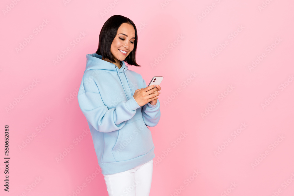 Photo of pretty cute lady wear blue hoodie communicating modern device empty space isolated pink color background Photo of pretty cute lady wear blue hoodie communicating modern device empty space isolated pink color background
