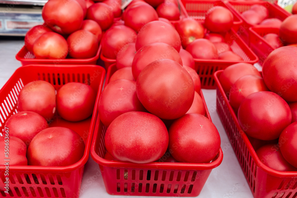 Lots of red tomatoes in plastic trays on the counter. Sale of tomatoes at the farmers' market. Red ripe tomatoes. Close-up.