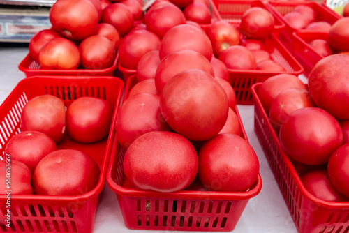 Obraz na płótnie Lots of red tomatoes in plastic trays on the counter. Sale of tomatoes at the farmers' market. Red ripe tomatoes. Close-up. w salonie