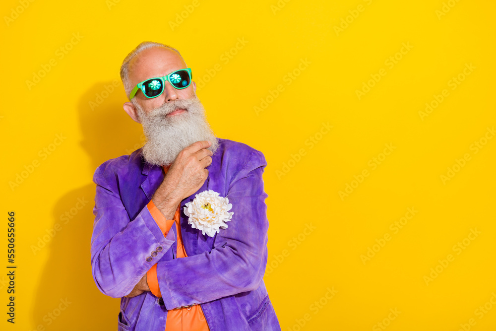 Portrait of minded serious aged person hand touch beard contemplate empty space isolated on yellow color background