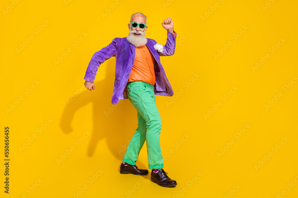 Full length photo of funky funny man wear purple velvet jacket walking dancing discotheque isolated yellow color background Full length photo of funky funny man wear purple velvet jacket walking dancing discotheque isolated yellow color background
