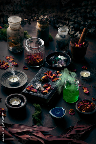 Witchcraft still life concept with smoking potion  spell book  herbs ingredients candles and magical equipment