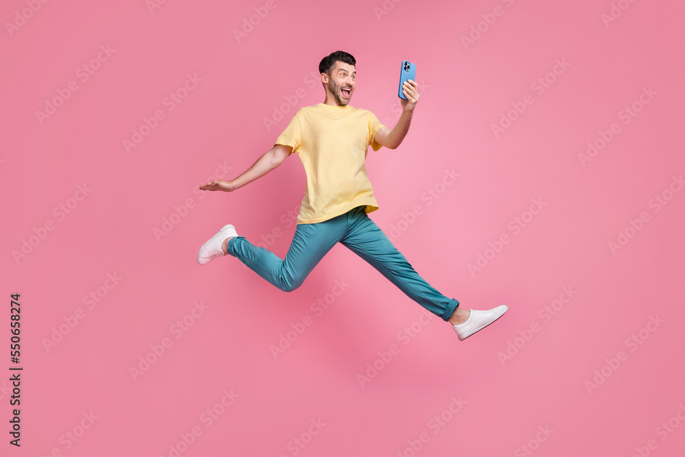 Full length photo of cheerful positive man blogger have iphone watching video meeting followers isolated on pink color background Full length photo of cheerful positive man blogger have iphone watching video meeting followers isolated on pink color background