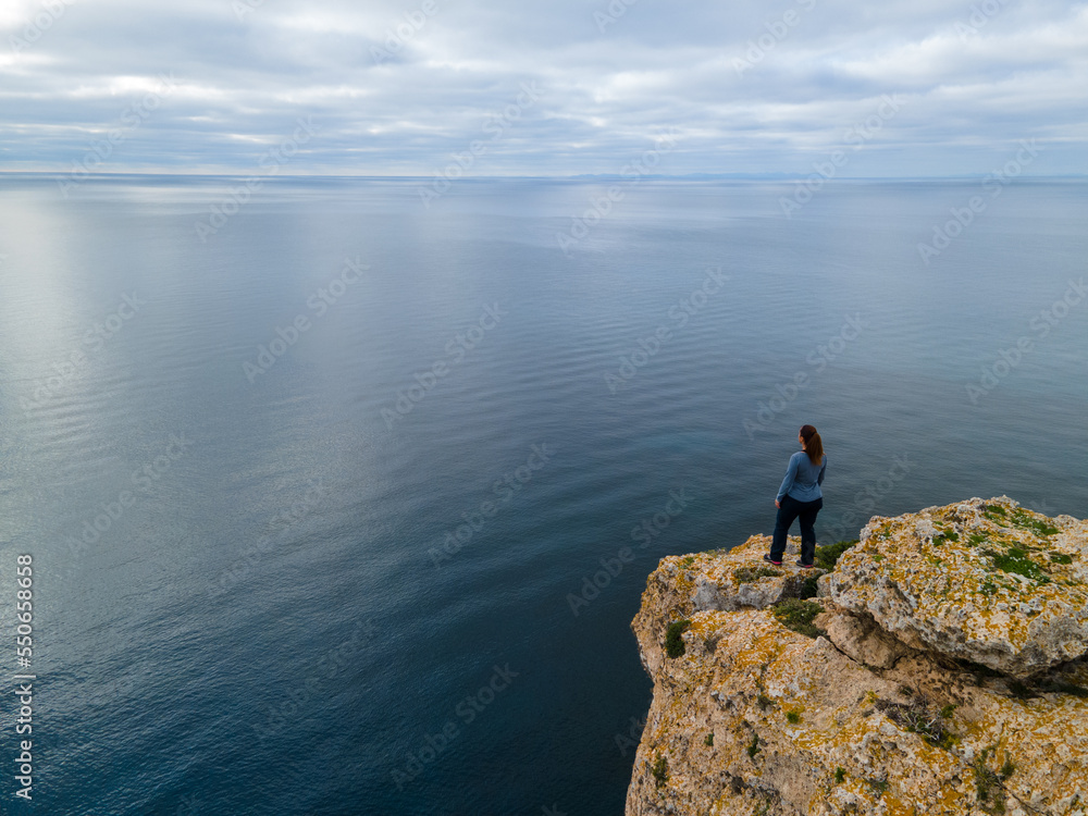 Person on cliff standing looking towards the horizon. Person on cliff standing looking towards the horizon.