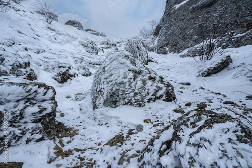 Trail between rocks with snow and ice to Mount Alenga near Southern Demerdzhi in snow and ice in spring. Crimea