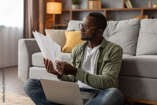 Carta da parati Sad pensive mature black man in glasses with laptop analyst document, work in li
