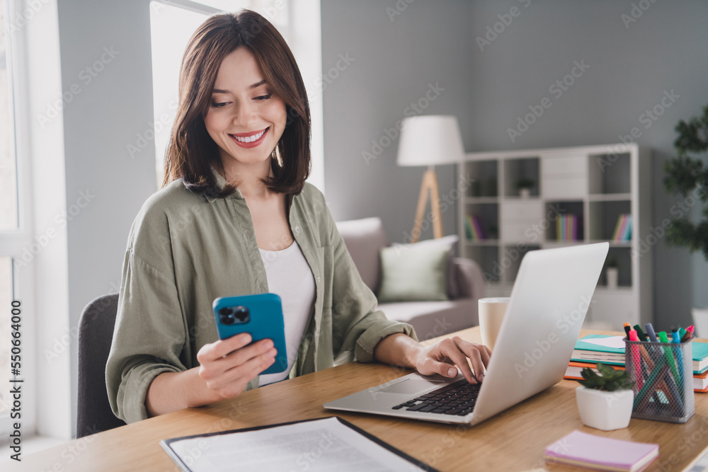 Portrait of attractive positive lady sit chair use wireless netbook telephone write typing modern office indoors Portrait of attractive positive lady sit chair use wireless netbook telephone write typing modern office indoors