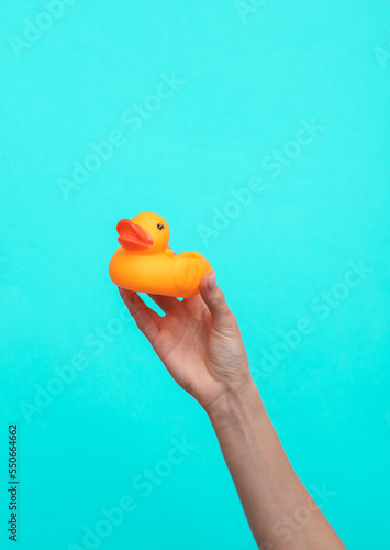 Obraz na plátně Female Hand holds a rubber duck on blue background.