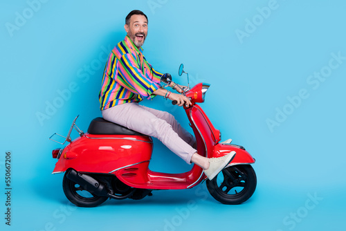 Profile side photo of cheerful stylish bearded man enjoying riding scooter excursion city empty space isolated on blue color background