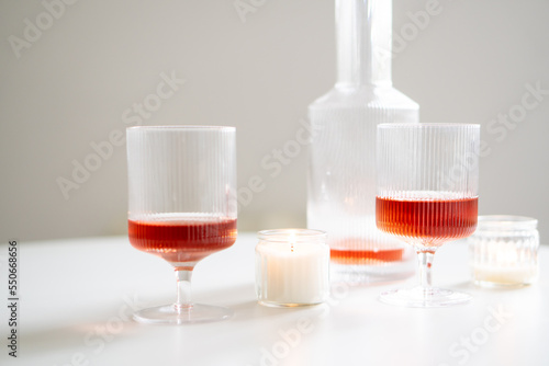 Rose wine in trendy ribbed wineglasses and decanter on white table