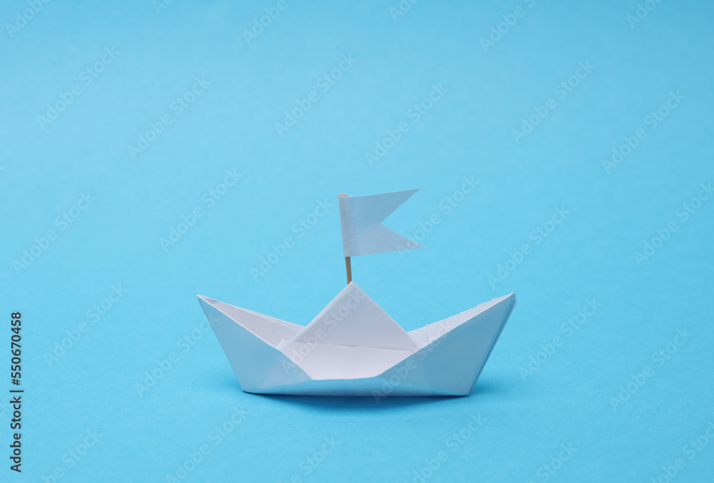 Paper boat with a flag on a blue background. Leadership concept Paper boat with a flag on a blue background. Leadership concept
