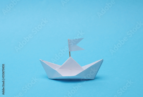 Paper boat with a flag on a blue background. Leadership concept