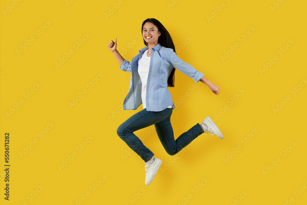 Glad happy cute millennial korean lady student in casual jumping and freezing in air enjoy freedom, has fun alone