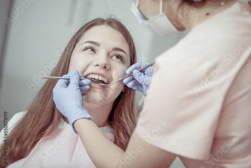 Young European woman being examined by the stomatologist. Beauty woman sitting in medical chair while dentist fixing her teeth at dental clinic. Dentist examining patient's teeth